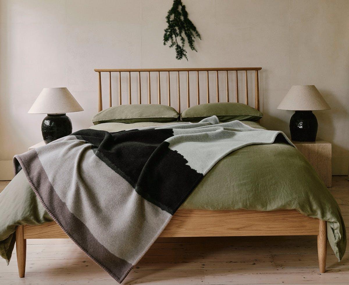 A bed with the BeggXCo Valatzu Sanna Bay cashmere blanket designed by Scottish Artist Hayley Mccrirrick